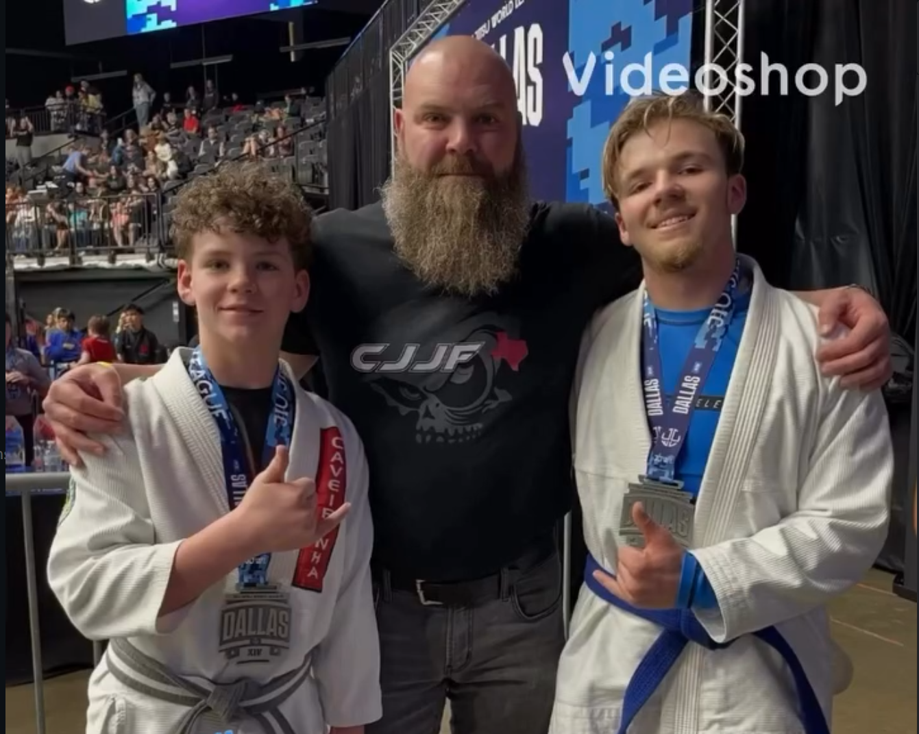 Eric Kelly, organizer and check-in lead, standing between his two teenage sons Gunner and Tucker, both in Brazilian Jiu-Jitsu gis and wearing competition medals.