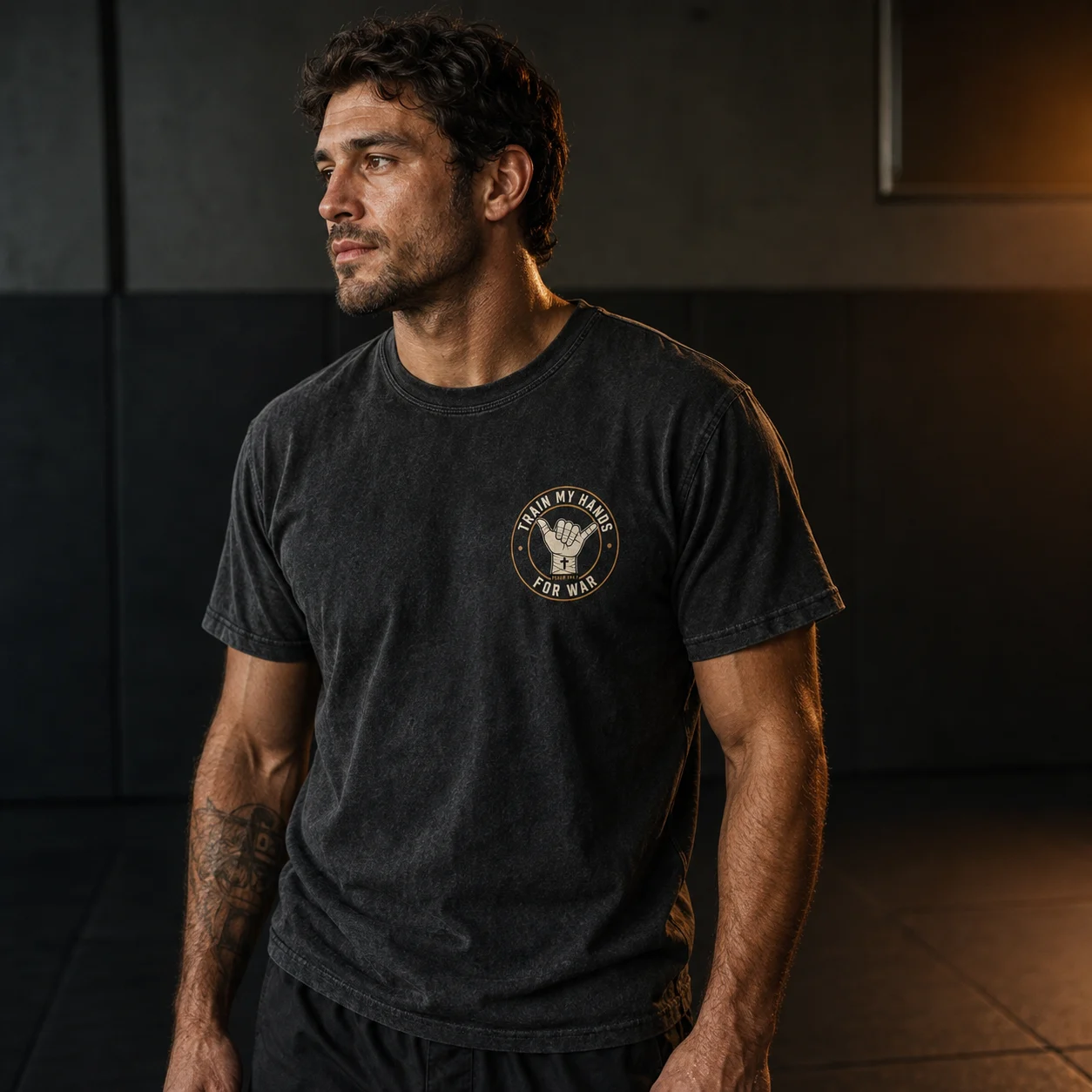 Member in the washed-black TMHFW foundation tee with the gold chest crest, mat-side