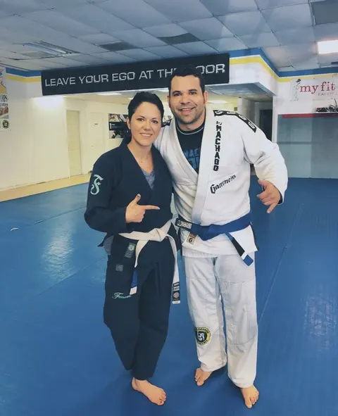 Felipe Soares in a white gi with a blue belt standing next to his wife Jeralin Soares in a black gi with a white belt at RCJ Machado in The Colony, Texas.
